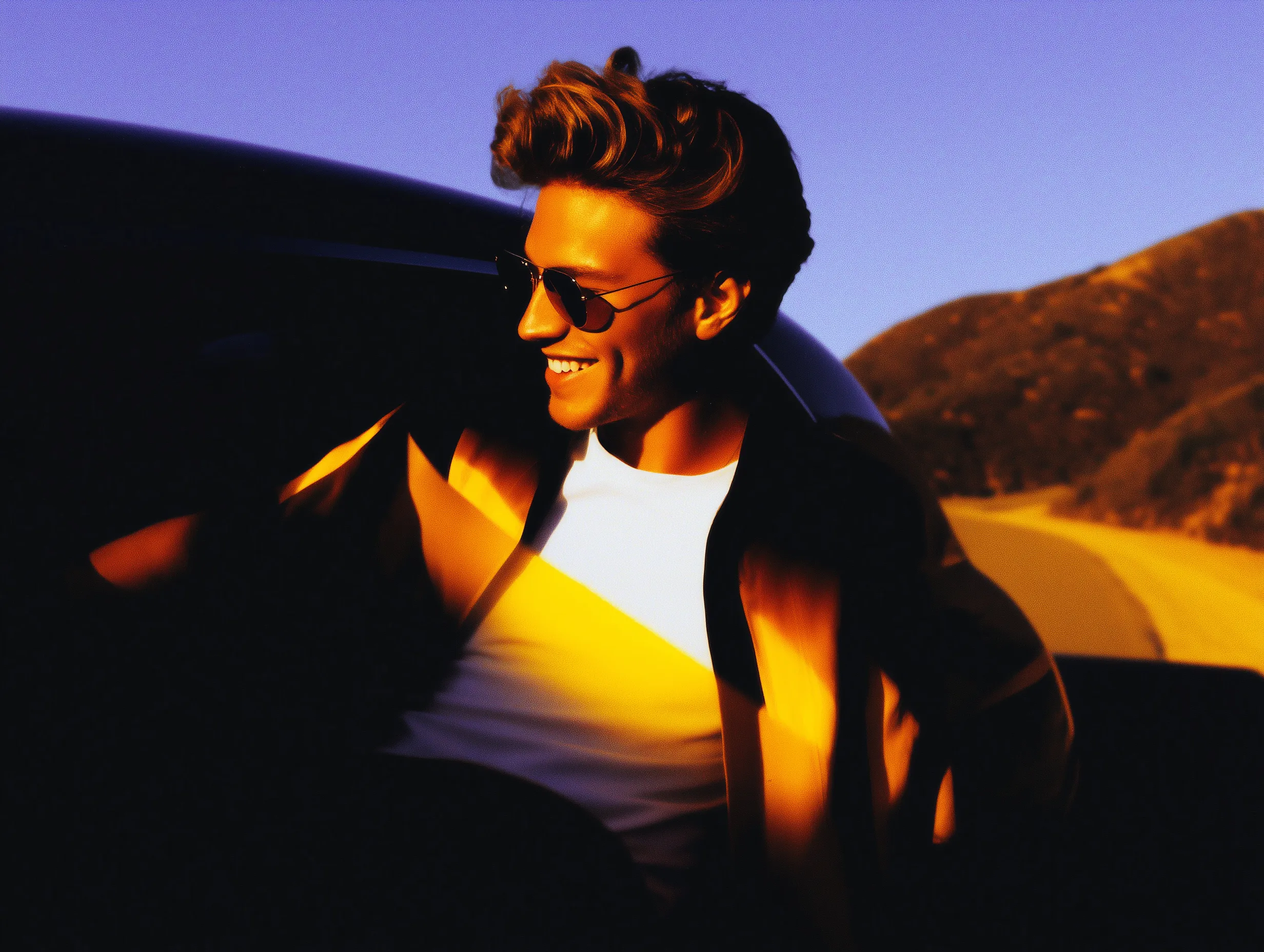 Man in sunglasses at golden hour on mountain road