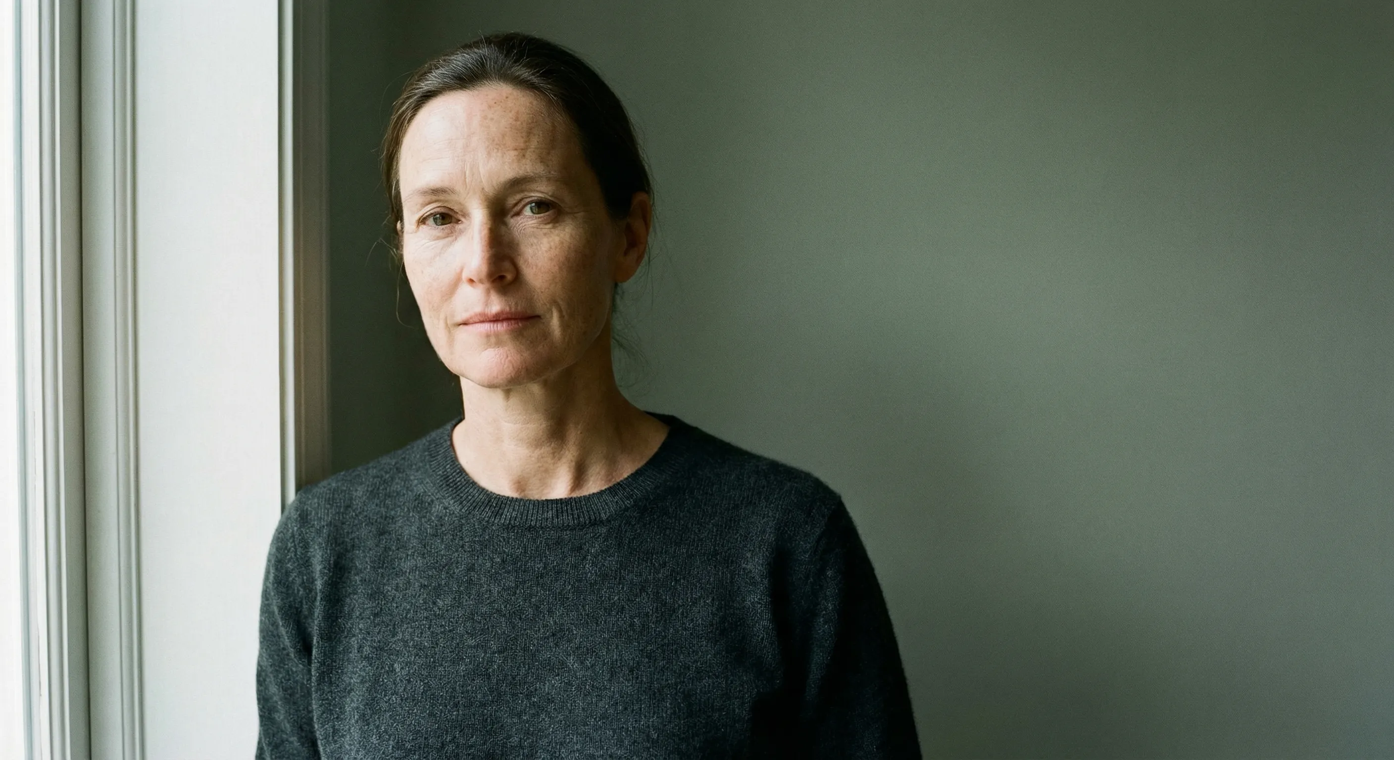 Thoughtful woman by window in muted light