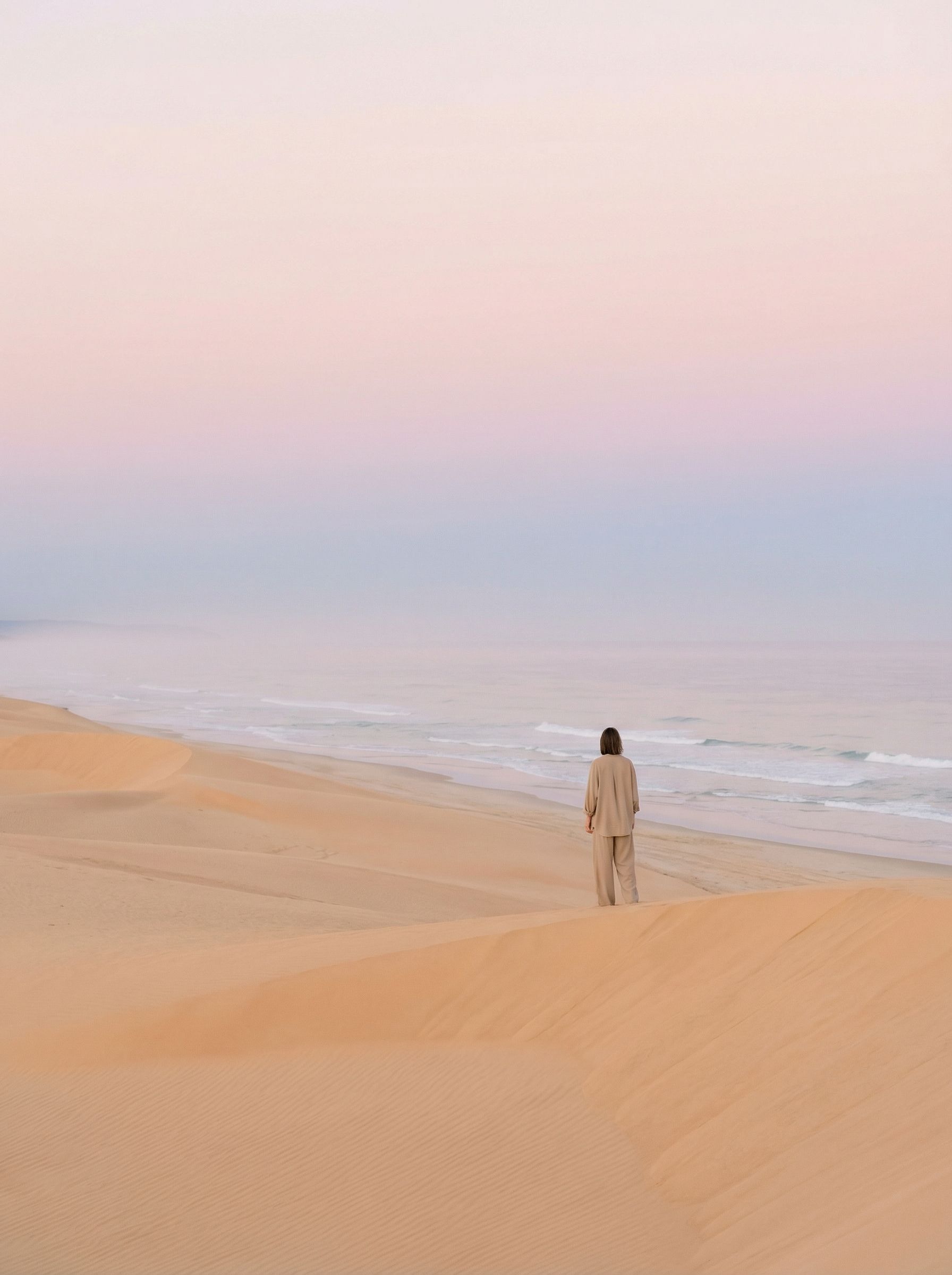 Solitary figure on serene pastel desert beach