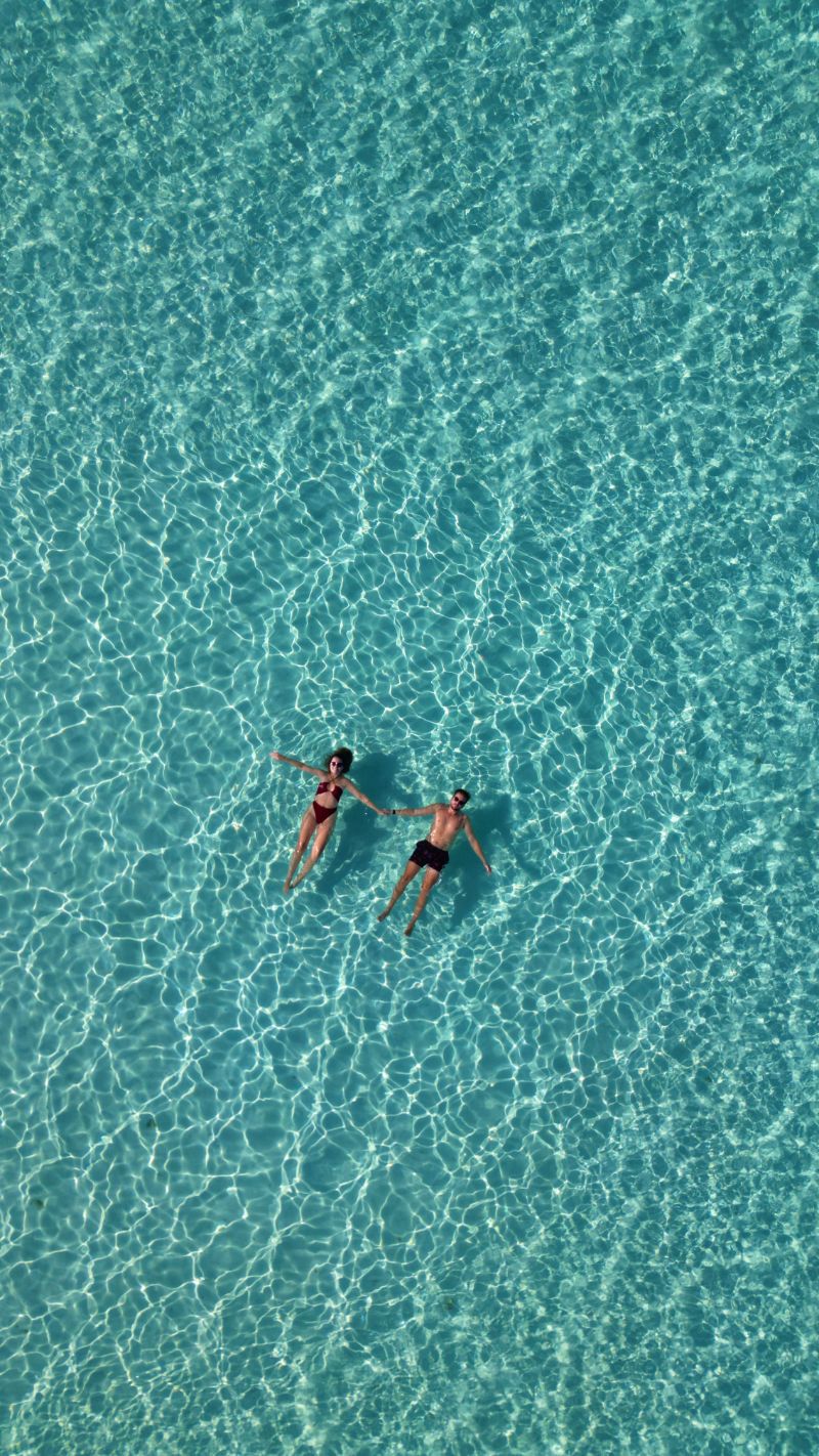 Aerial View of Couple Floating in Clear Sea