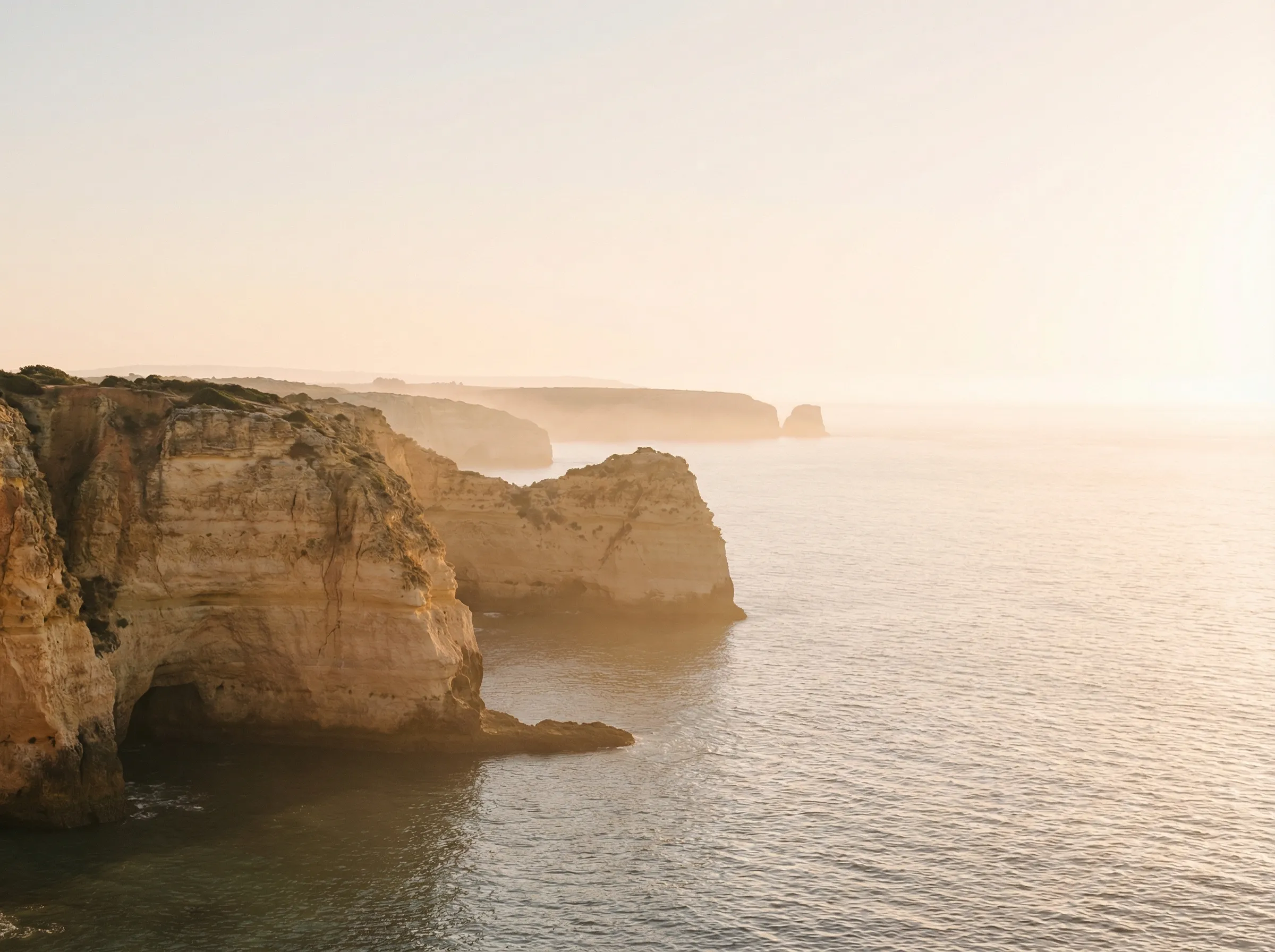 Sunlit sea cliffs in soft coastal haze