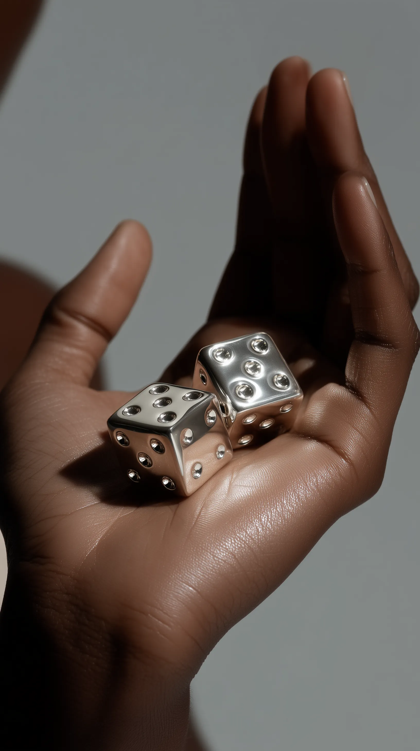 Hand Holding Metallic Dice in Soft Light