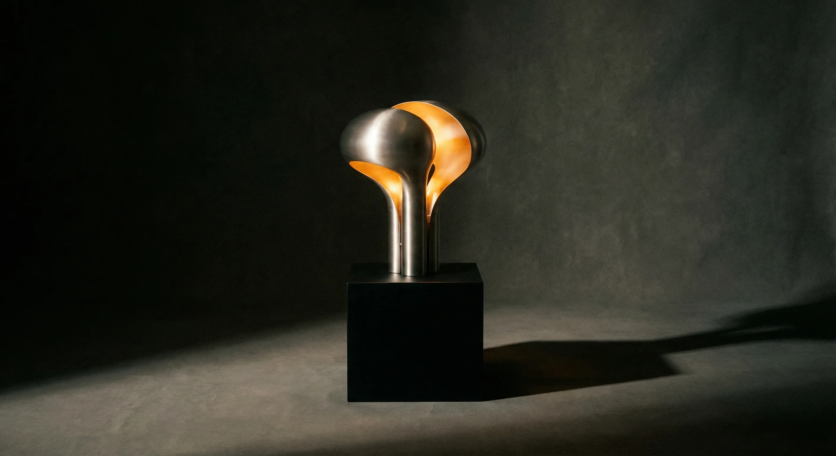 Sculptural metal lamp on dark pedestal