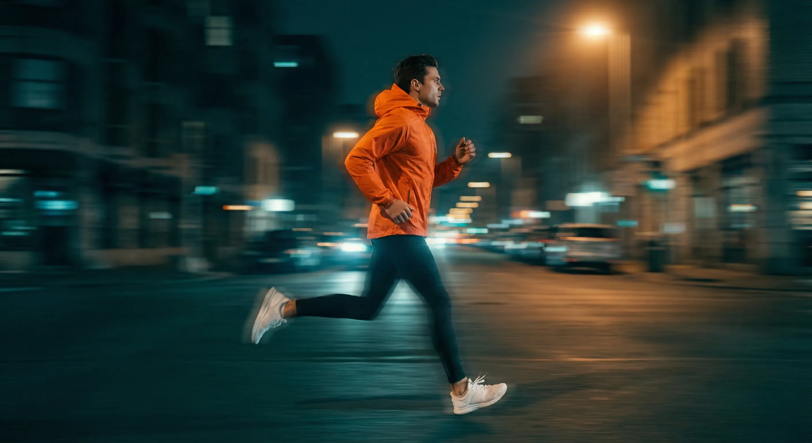 Night runner in orange jacket on city street