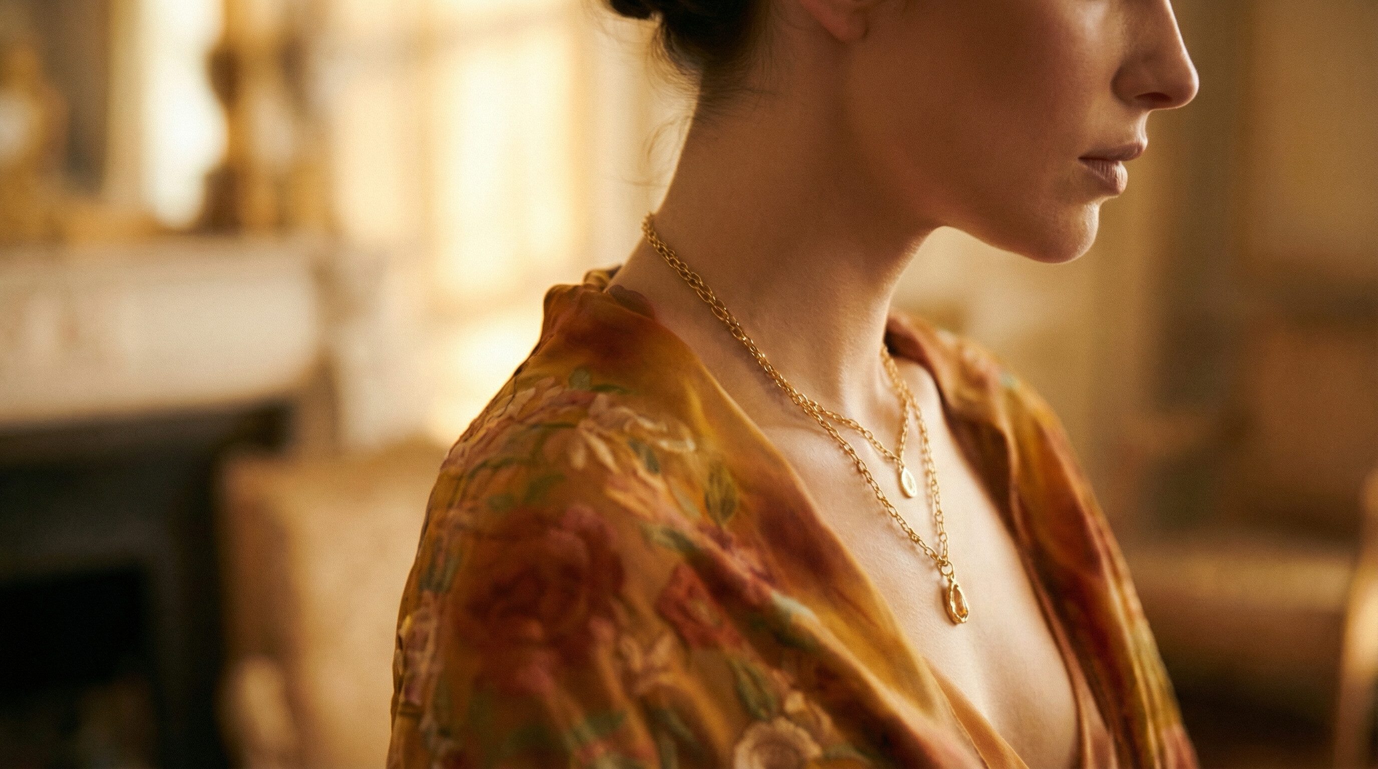 Woman in floral robe wearing layered gold necklaces
