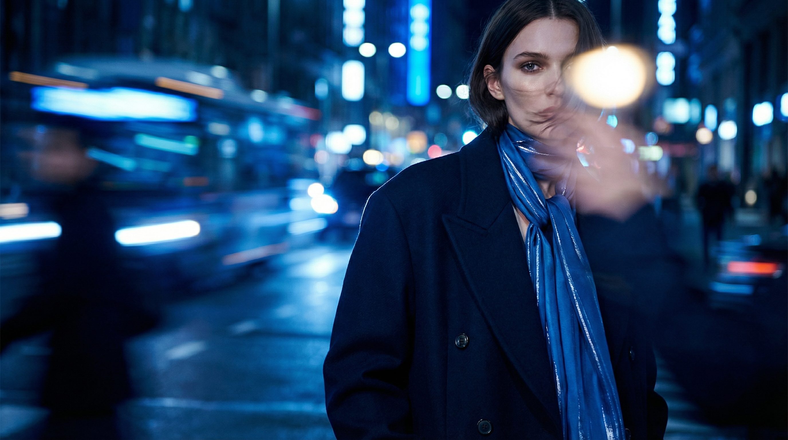 Woman in blue coat on blurry night city street