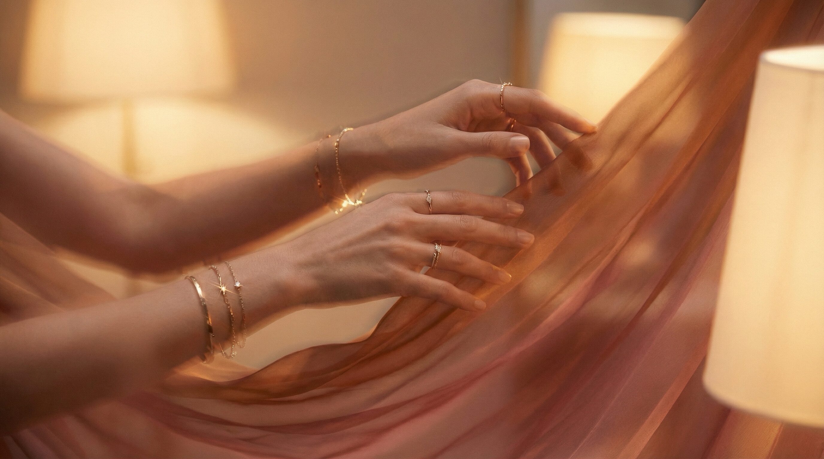 Elegant hands with gold jewelry and silk fabric