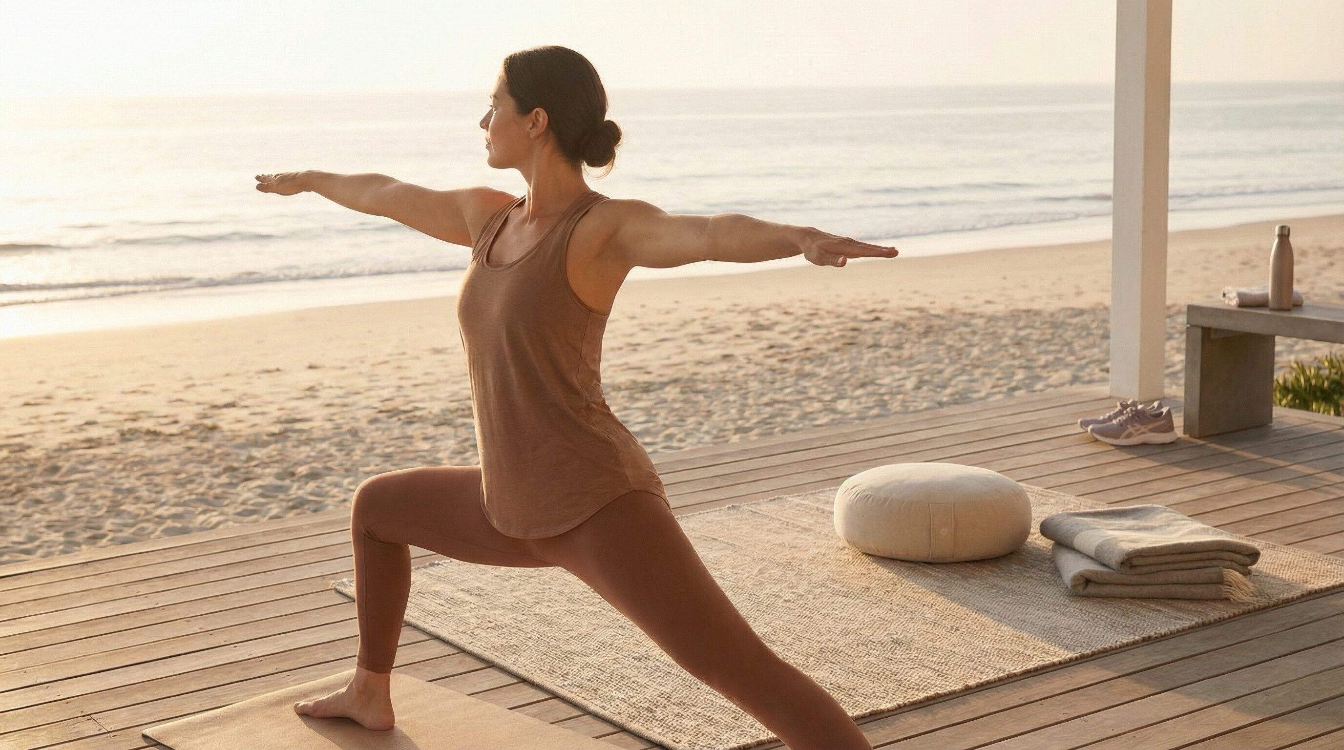 Woman practicing yoga on beach deck at sunrise