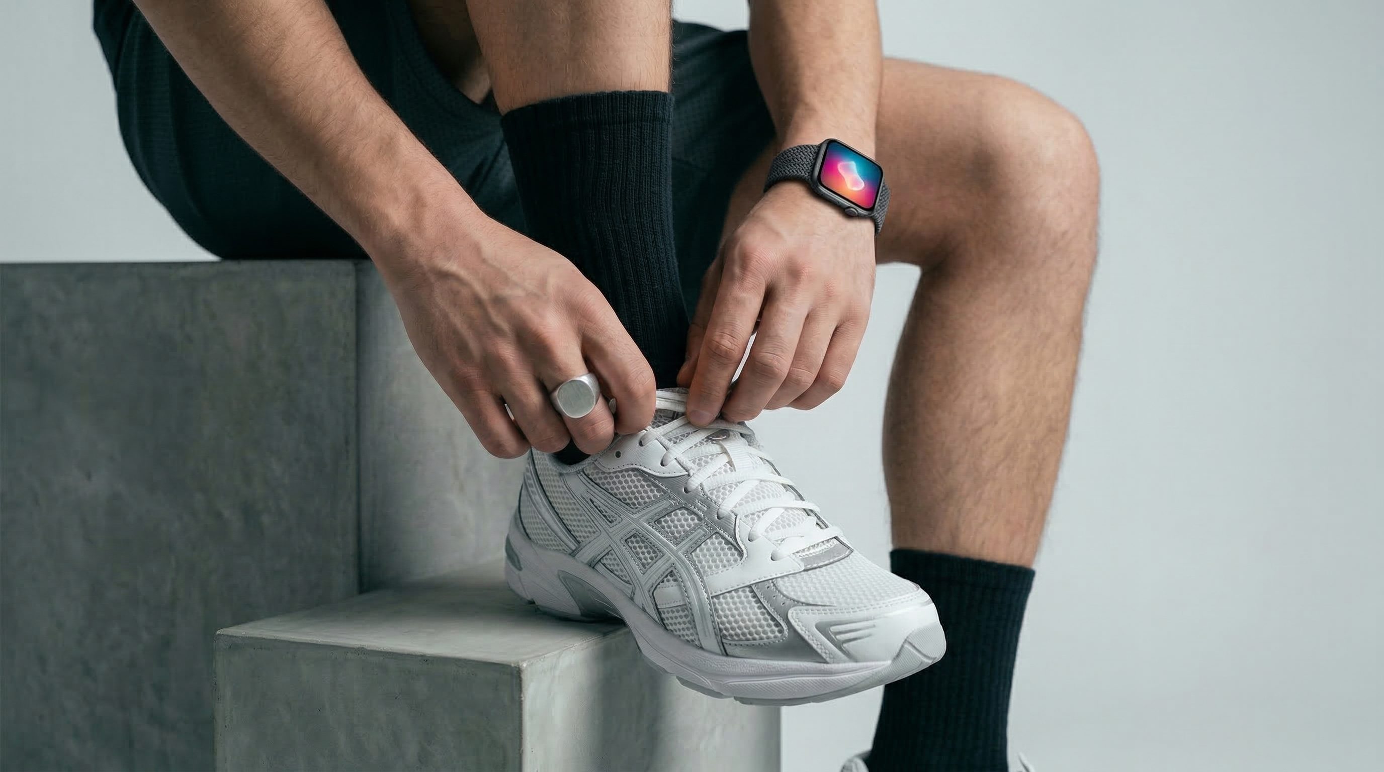 Athlete tying white sneaker with smartwatch