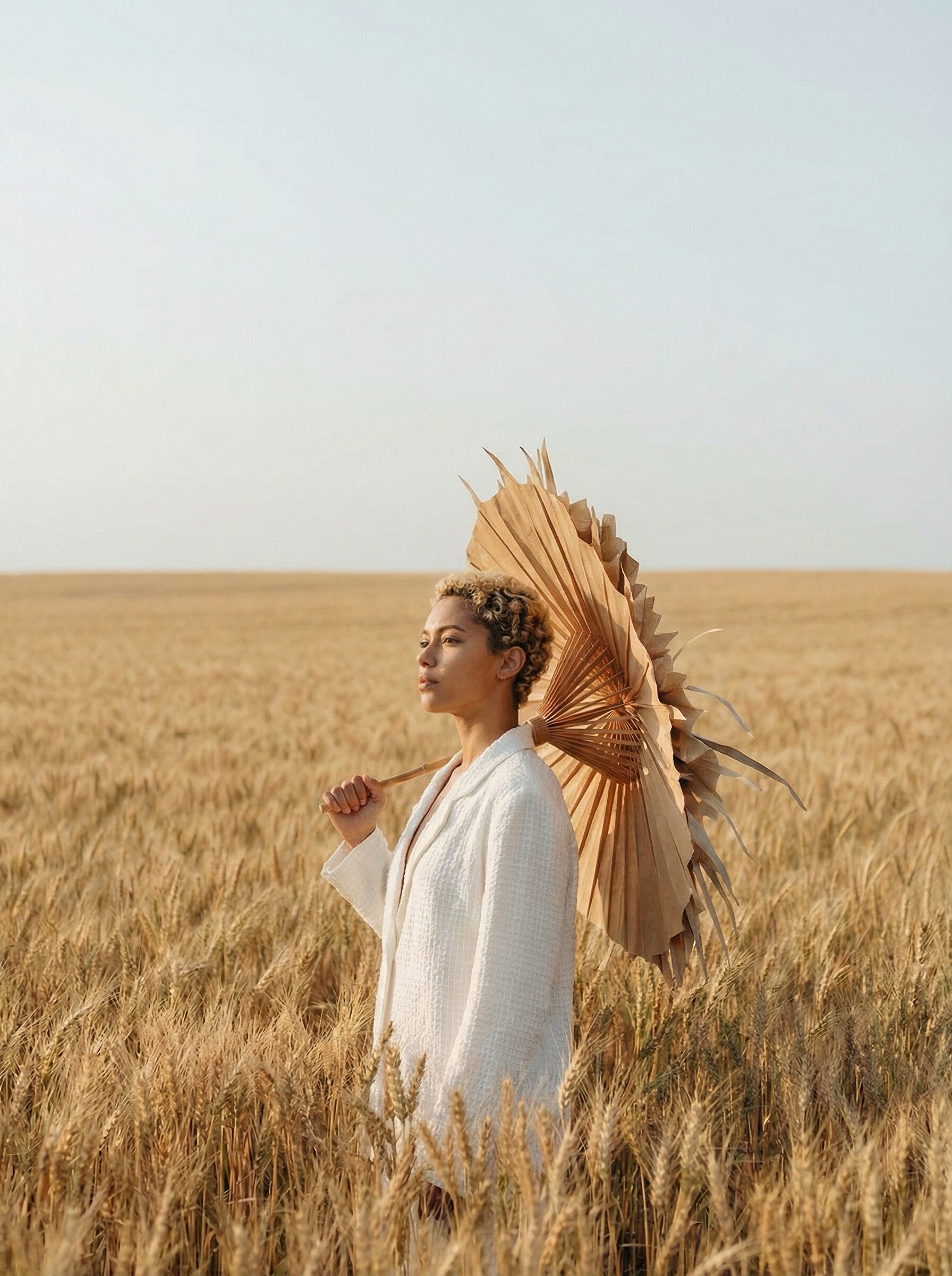 Woman with parasol in golden wheat field