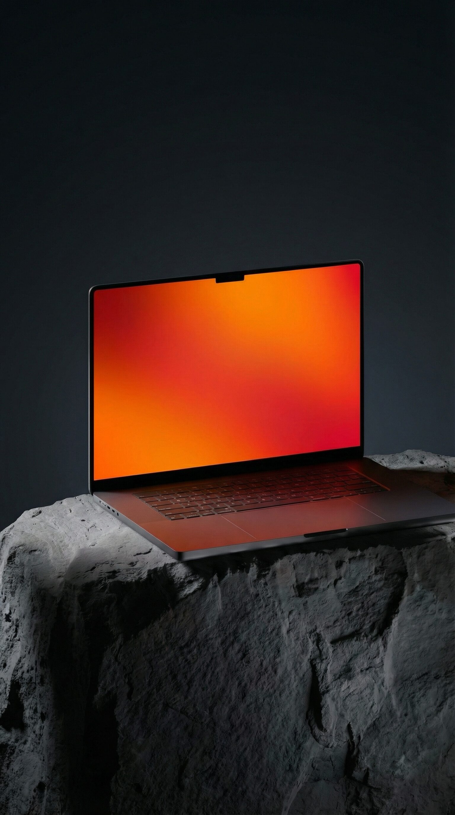 Laptop with orange gradient screen on rock